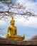 Golden statue of a sitting buddha, flanked by two Naga serpents in Thailand.