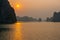 Golden sun in hazy sky above dramatic rocks and islands in Halong Bay