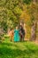 In the golden sun a portrait of a blond smiling girl with her horse and foal in the forest. Wearing a green dress. Selective focus