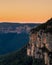 Golden sunrise across orange sandstone cliffs above eucalyptus trees in the Gross Valley in the Blue Mountains, west of Sydney,