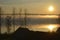 Golden sunrise over the lake in the fog. Smoke over water and silhouettes of small houses and trees