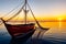 Golden Sunrise Over Ocean: Weathered Fishing Boat with Nets Navigating Calm Sea Waters