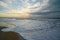 Golden sunset on the beach and low sea waves brake the shore.