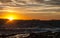 Golden sunset behind Conejera Islands. Choppy waters of Balearic sea churns waves on rocks along shore.