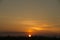 Golden sunset with light cirrus clouds and low trees on the skyline.