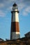 Golden sunset light hitting the side of a tall stone lighthouse. Montauk Point, NY