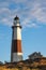 Golden sunset light hitting the side of a tall stone lighthouse. Montauk Point, NY