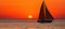 Golden Sunset over Ocean with Sailboat on Horizon, Magnifying Grandeur and Tranquility