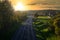 Golden sunset over a road in a residential area surrounded by green lawns and lush trees