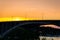 Golden sunset with people cycling on a bridge.