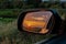 A golden sunset seen in an outside rear view mirror