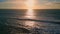 Golden sunset sky rippling ocean surface drone view. Sea reflecting sunlight