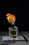 Golden tequila with grilled shrimp on a dessert fork on a black background