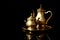 Golden tray with teapot and sugar bowl on black background