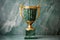 a golden trophy cup on a marble column with a green background