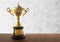 Golden trophy on wooden table over abstact white bokeh background. Winning awards with copy space.