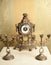 Golden vintage metallic clock with two candlesticks for three candles on white table. Luxurious art objects