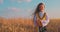 Golden wheat field and little girl with Bulgarian folklore costume during harvest time and sunset