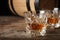 Golden whiskey in glass with ice cubes on wooden table.