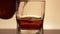 Golden whiskey is poured into a glass in slow motion