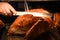 Golden whole roast turkey joint of meat being carved with a knife and the hand is visible