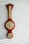 Golden wooden vintage barometer hangs on white wall in sunlight