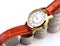 Golden wrist watch on rising pile of silver coins