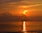 Golden Yellow Shining Sun Rising at Horizon with Reflection in Sea Water with Warm Colors in Clouds in Morning Sky