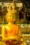 Golden yellow statue of Buddha sitting meditating and praying