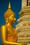 Golden yellow statue of Buddha sitting meditating and praying