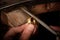 Goldsmith hand holds a golden ring on the wooden workbench and w