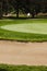 Golf ball on a greenside bunker sand trap hazard in a golf cours