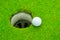 Golf ball on lip of cup, Golf ball and golf hole on green grass.