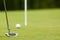 Golf ball and putter near green and flag