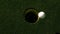 Golf ball rolling into the hole on putting green