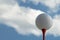 Golf ball on tee against cloudy sky