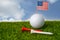 Golf ball with USA flag and tee on green grass, most popular sport in the world