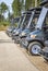 Golf cars or golf carts parked in a row outdoors on a sunny day.