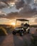 golf cart backlit by setting sun on 18th hole of course