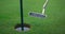 Golf club hitting ball in course hole. Golfing player swinging putter on fairway