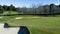 Golf course green with flag, bunkers, dam and tree lined fairway