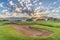 Golf course homes lake and mountain under sun and cloudy blue sky at sunrise