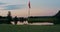 Golf course red flag in golfing hole. Flagstaff on empty green course sunset.