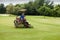 Golf course worker mows the grass