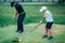 Golf Lessons. A golf Instructor and a boy practicing on a Golf Practice Range