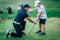 Golf Lessons. Golf instructor giving game lesson to a young boy