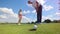 Golf player puts a ball into a hole at a golf course while woman is watching.