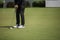 Golf player at the putting green hitting ball into a hole