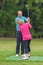 Golf pro correcting a lady golfers grip