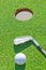 Golf putter ball near the hole in the vertical format.